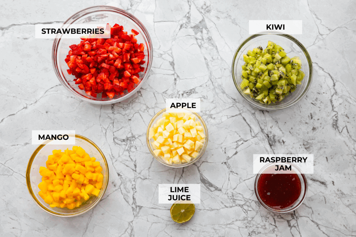 Vibrant fruit salsa is a fresh, juicy twist on your favorite snack! Sweet berries, tropical mango, and a splash of lime always steal the spotlight! Especially when served with crispy cinnamon chips! Overhead shot of labeled ingredients.