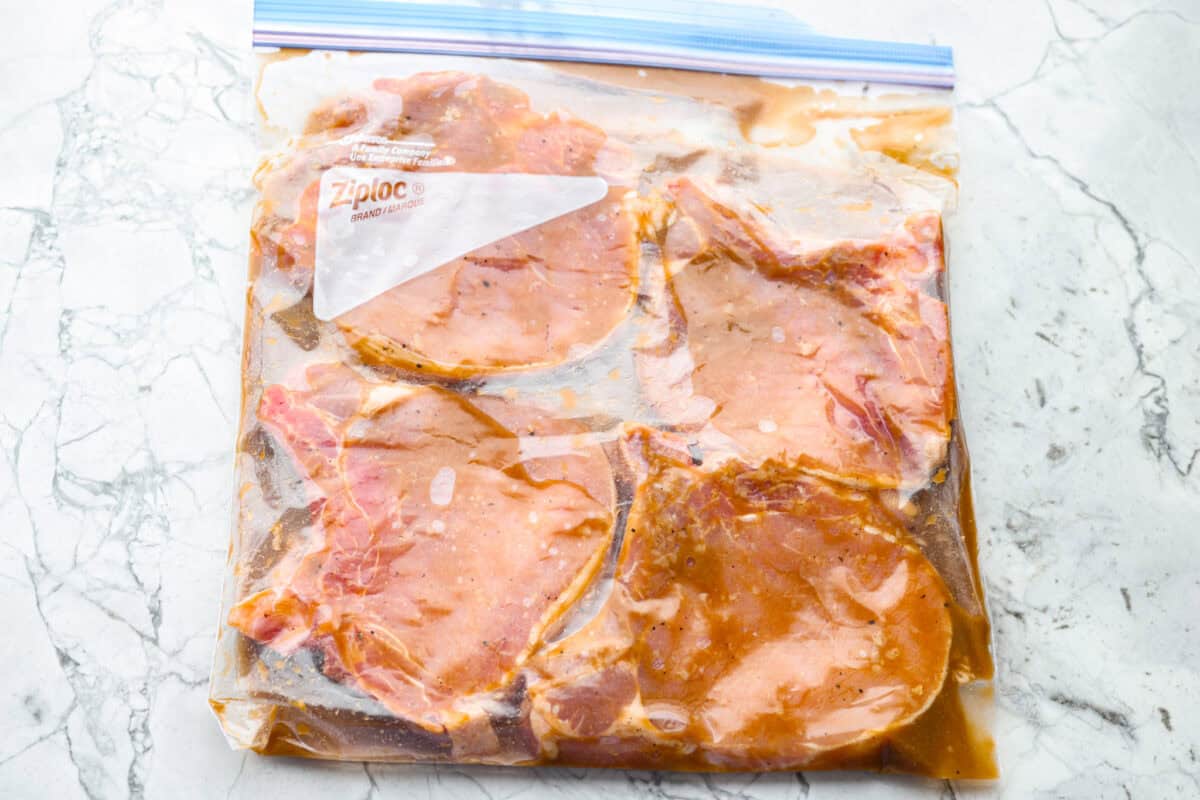 Stop making boring pork chops. You NEED this pork chop marinade, with soy sauce, brown sugar, garlic, Dijon, and citrus! It all comes together for the most juicy, tender, flavor-packed pork chop you've ever had! Pork chops in marinade in a sealed gallon sized zip lock bag.