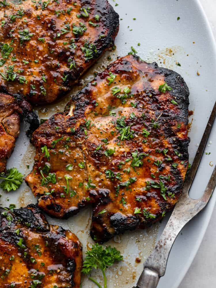 Stop making boring pork chops. You NEED this pork chop marinade, with soy sauce, brown sugar, garlic, Dijon, and citrus! It all comes together for the most juicy, tender, flavor-packed pork chop you've ever had! Closeup of grilled pork chops.
