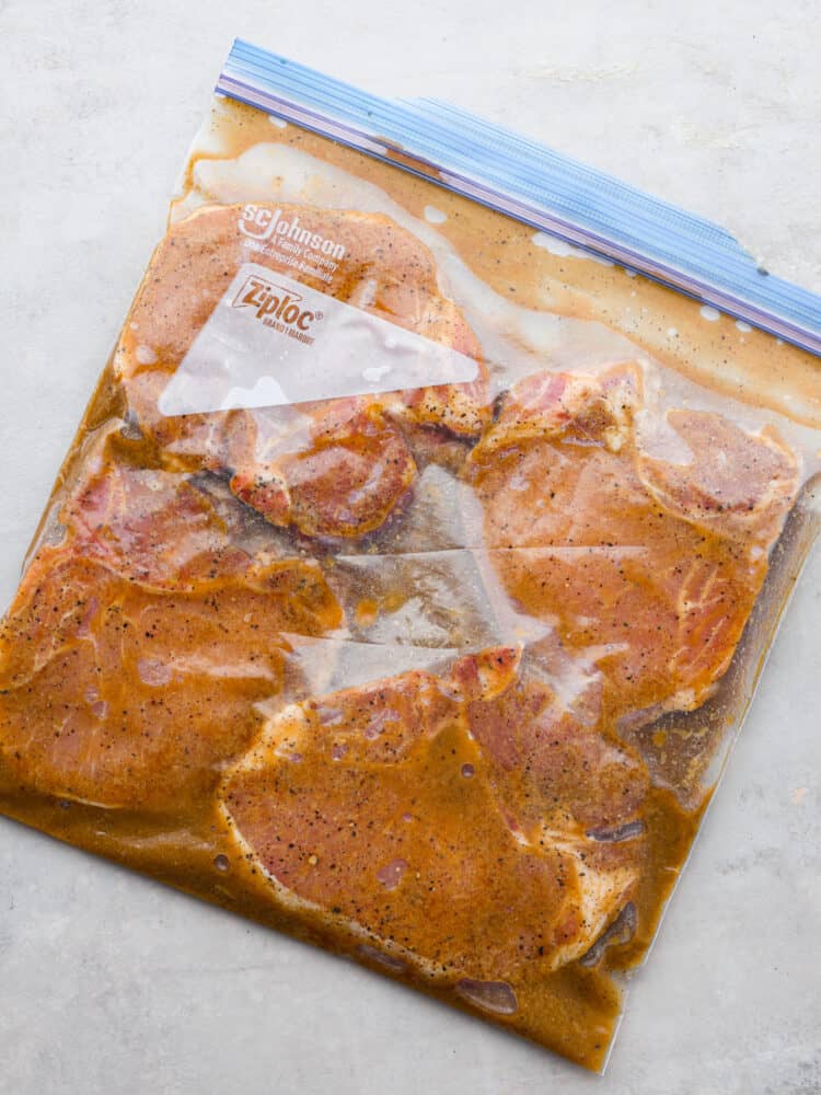 Stop making boring pork chops. You NEED this pork chop marinade, with soy sauce, brown sugar, garlic, Dijon, and citrus! It all comes together for the most juicy, tender, flavor-packed pork chop you've ever had! 4 pork chops marinating in a Ziploc bag.